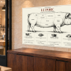 Tableau culinaire Porc — 60 × 40 cm — Plexiglas — vue en perspective Tableau culinaire Porc — 60 × 40 cm — Plexiglas — vue en perspective. Mise en situation sur un mur en pierre claire.